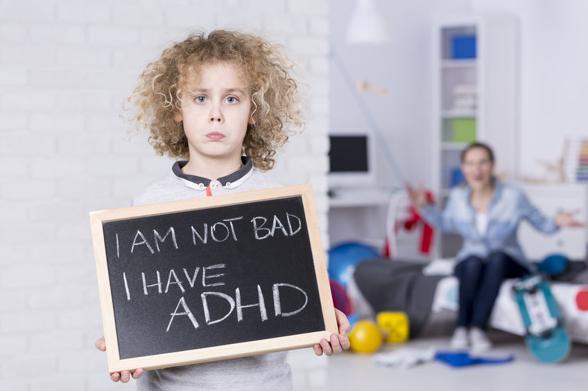 A boy holding up a small chalk board with the phrase “I am not bad. I have ADHD.”